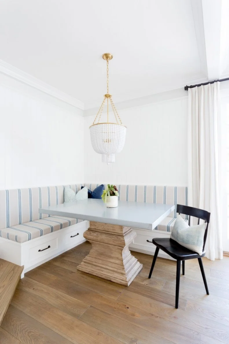 A built-in banquette with easy-to-clean striped fabric is the perfect kid-friendly choice for a cozy breakfast area. Drawers underneath provide extra storage, and a beaded chandelier makes for a striking focal point. 