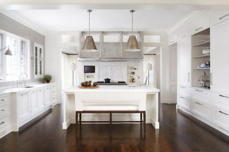 Instead of the traditional barstools at the breakfast bar, designers chose to update this neutral, farmhouse kitchen with a bar bench for a bit of modern flair. 
