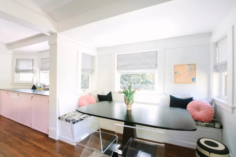 With a built-in banquette, two acrylic chairs and a modern table, this breakfast nook is a stylish space for sipping coffee and reading the morning newspaper. Pink and black pillows keep the spot extra comfortable.