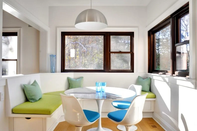 Green cushions, teal accents and a dome-like light fixture all give this breakfast nook a touch of midcentury style. A tulip table centers the space, with a banquette and three chairs for extra seating. 