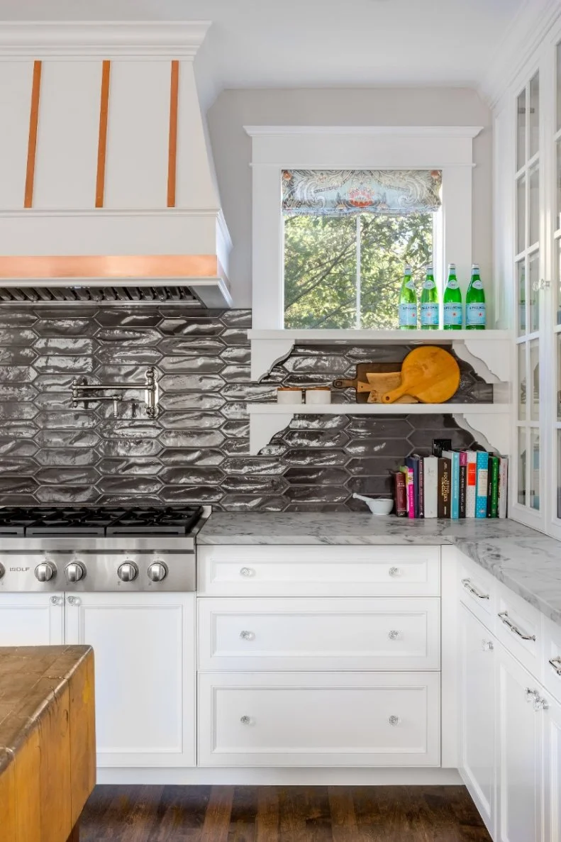 Two open shelves allow light to flood in through this kitchen window, but also provide storage.
Countertops are gray-and-white quartzite.