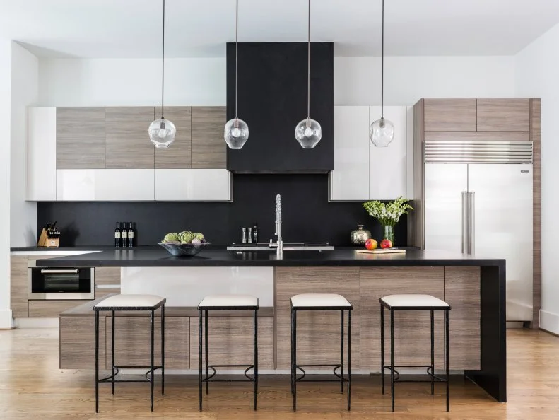 The homeowners wanted a texture-rich space with a simple feel, so designers set out to achieve that goal by using cabinets that were a mix of wood and back painted glass. Black granite was added to the countertops, backsplash and range hood. This creates a sleek, streamlined design for the heart of this sophisticated home. 