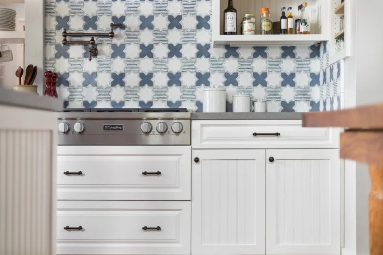 The backsplash is the star attraction in this lovely kitchen, the graphic pattern bringing zip and color to the white cabinets and drawers.