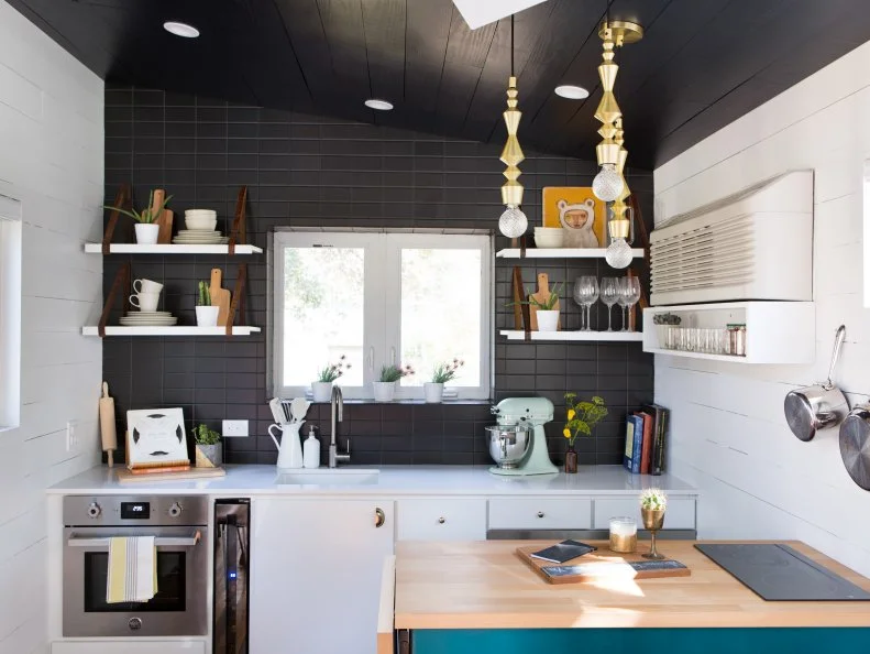 This tiny black and white kitchen designed by Kim Lewis Designs is nine feet wide. The countertops are by Silestone, lights by CB2 and tile by Daltile.