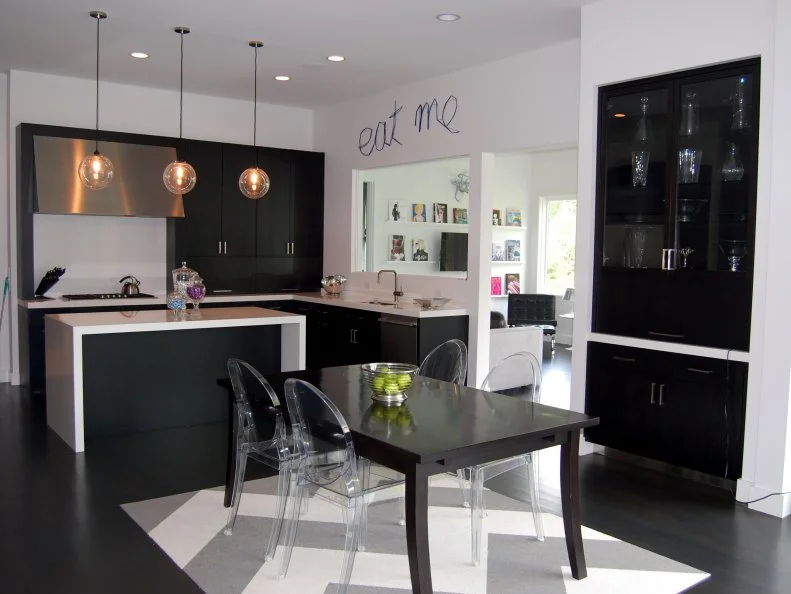 The designer of this modern home's interior incorporated the owners' extensive art collection and created installations throughout the space. Here, a cheeky 'Eat Me' sign floats above the kitchen's peek-through window.