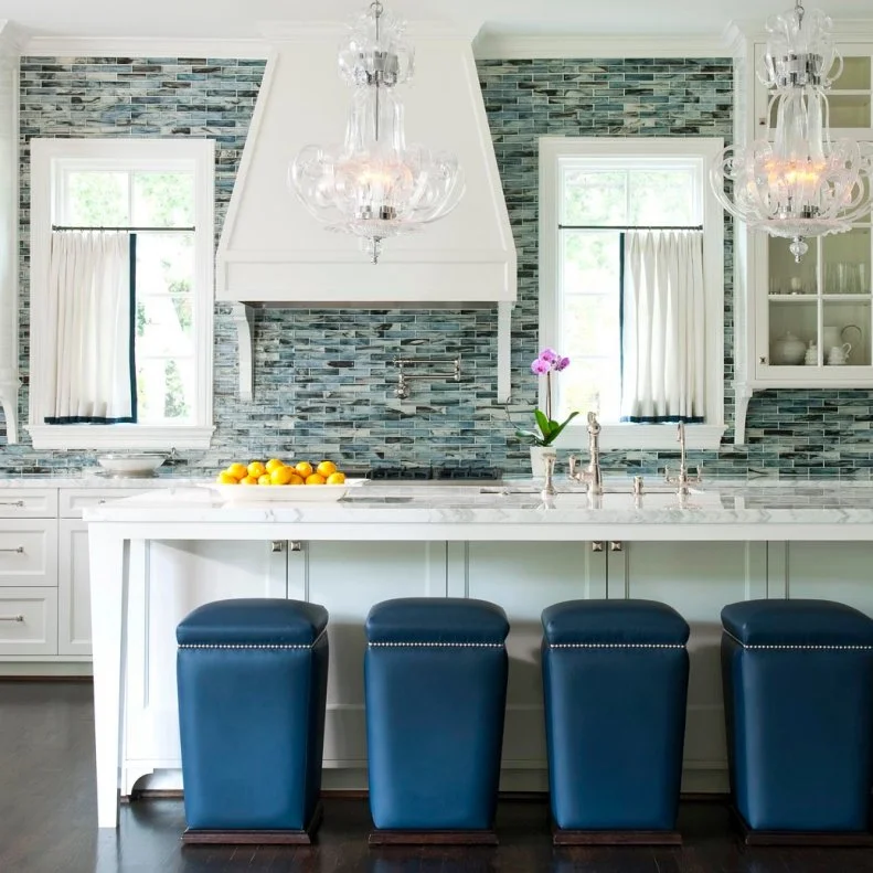 A dramatic, pearl-finish backsplash and contemporary stools modernize this renovated traditional kitchen for fashion-forward homeowners, packing it with charm and interest. Designer Marci Barnes expanded the original kitchen footprint and opened up the room to the dining area and attached sunroom to further update the space.