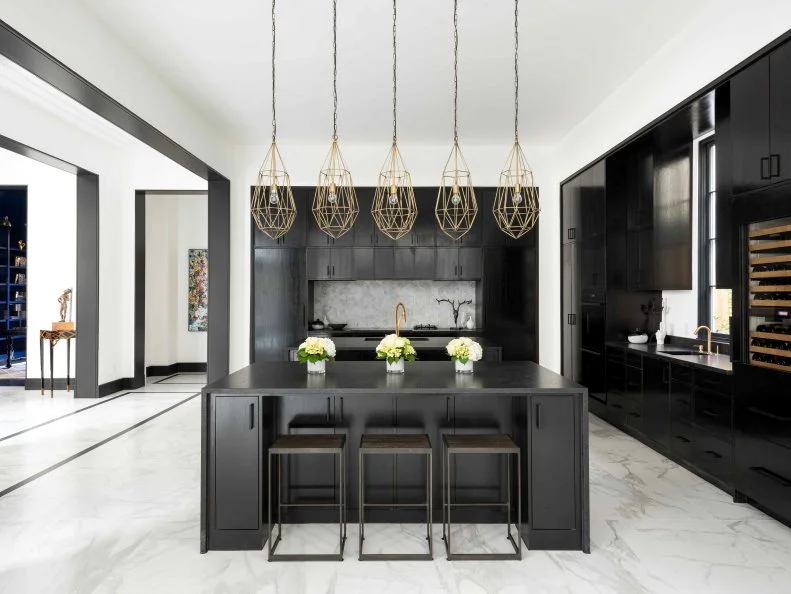 The black-and-white color scheme creates a clean, sophisticated look in this open floor plan kitchen. Floor-to-ceiling sleek black cabinets provide tons of storage, while a large island is the perfect spot for the whole family to gather for meals. 