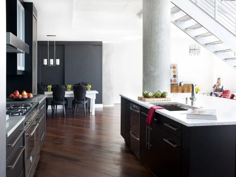 The large black kitchen island with white marble countertop compliments a bank of contemporary cabinets and stainless steel appliances. The stylish black and white island has a built-in sink and pull out drawer dishwasher.