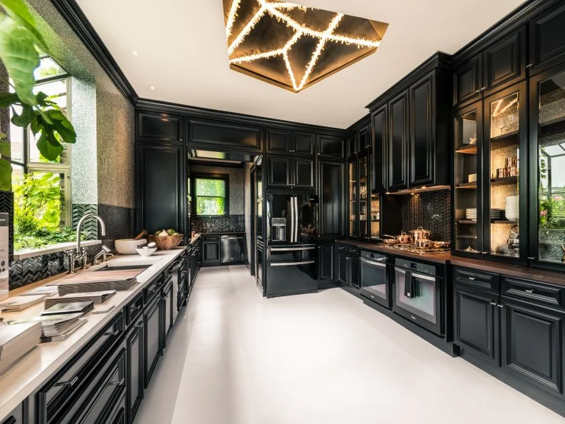 Rich black, enameled cabinetry with accents of Peruvian walnut are the dramatic cornerstone of the San Francisco Decorator Showcase 2014 kitchen. Designer Steven Miller completed the sophisticated look with brushed and polished metal hardware, white stone counters and geometric glass tiles, and a custom quartz crystal-encrusted ceiling cove crowns the space.
