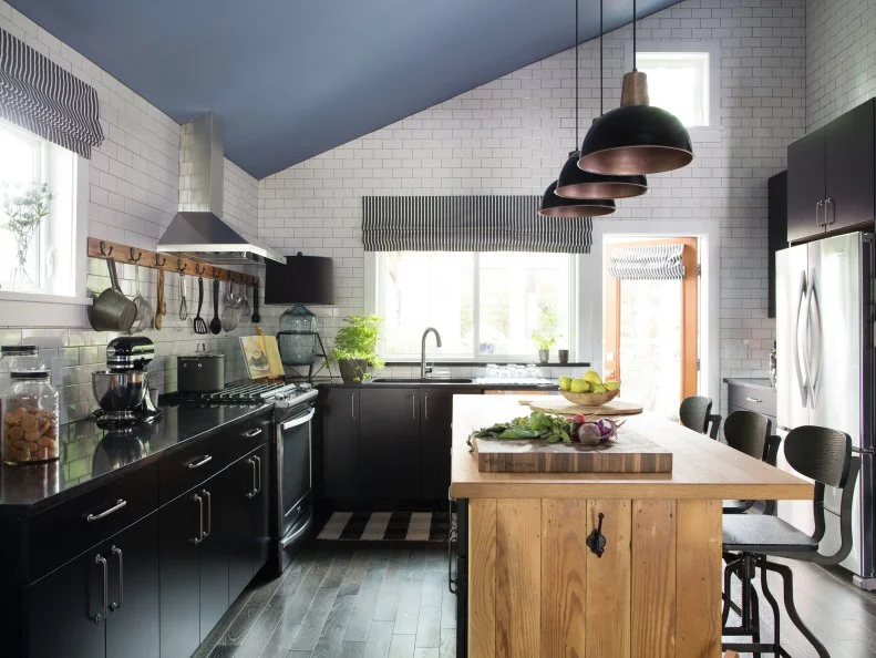 A large farmhouse style kitchen combines classic black and white with a spacious butcher block island for a clean and simple finish.