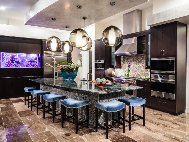 Oversized glass pendants hover like bubbles above the kitchen island, a fun tie-in to the built-in aquarium along the back wall. Blue barstools and the aquarium's neon lights add a welcome dash of color.