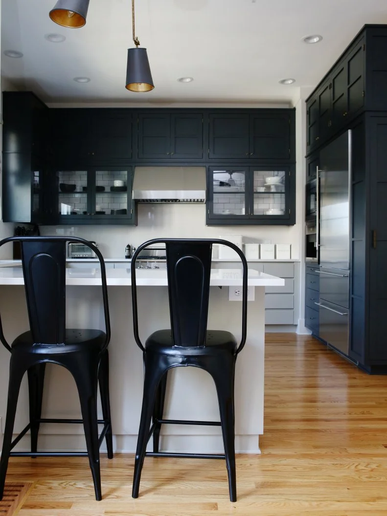 Black industrial barstools pull up to clean Caesarstone countertops for a casual dining spot in this spacious kitchen. Hardwood floors add warmth to the space, while a sleek light fixture brings a contemporary vibe to the room. 