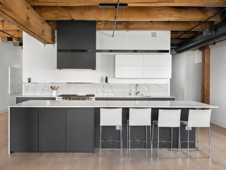 Tucked underneath unfinished wood beams, this loft's modern kitchen keeps a clean, spare look in crisp black and white.
