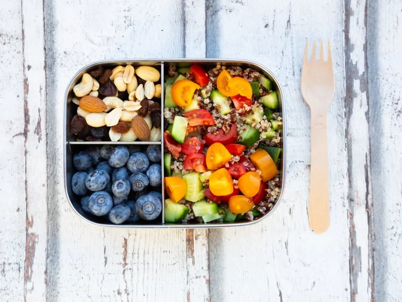 Lunchbox with quinoa salad with tomato and cucumber, blue berry and trail mix