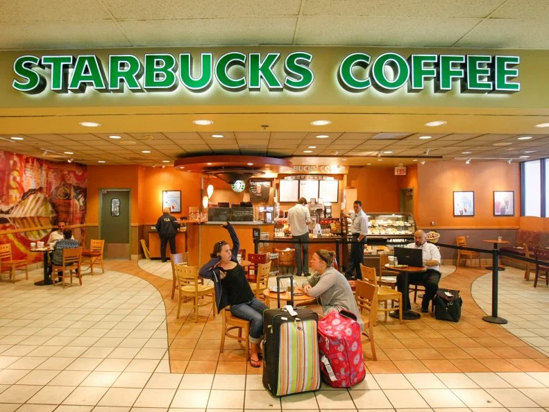 Travelers relax at Starbucks Coffee located in Terminal 2 at LAX Airport. Officials are aiming at updating the terminals at Los Angeles International Airport with trendy shops and enticing eateries that would do much to spruce up a drab gateway often pummeled by low passenger satisfaction surveys.  (Photo by Allen J. Schaben/Los Angeles Times via Getty Images)