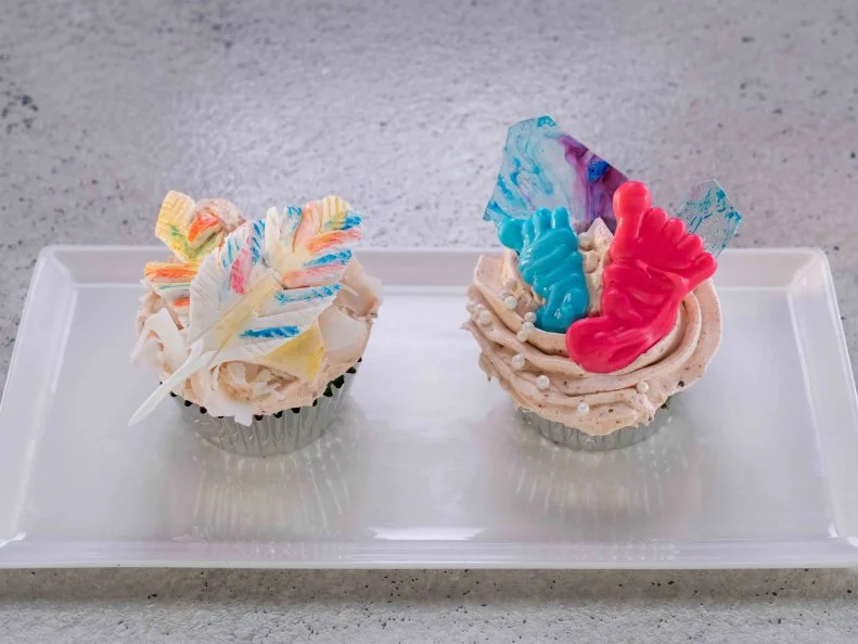 Contestant Jerry Tapia's dish baby feet with isomalt shard and feather, featuring vanilla cardamom spice cupcake with a strawberry and chili spiced Italian meringue buttercream, during the first challenge, as seen on Cupcake Championship, Season 1.