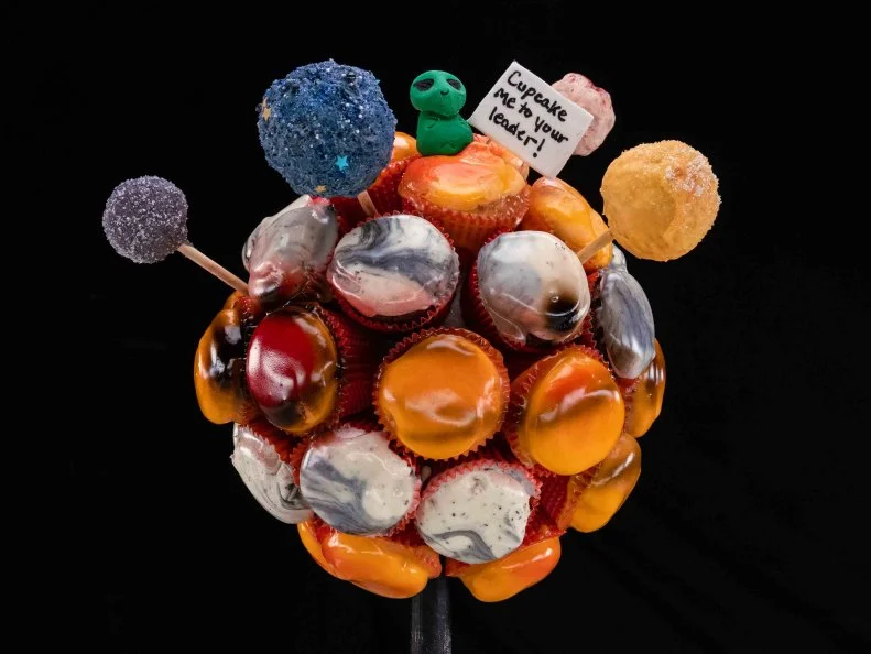 Contestant Annie Chang presents her dish Saturn and Rings, with lemon cupcake with cream cheese frosting filling topped with mango buttercream, and matcha cupcake with black sesame buttercream, and the rings are gum paste and fondant, during the final challenge, as seen on Cupcake Championship, Season 1.