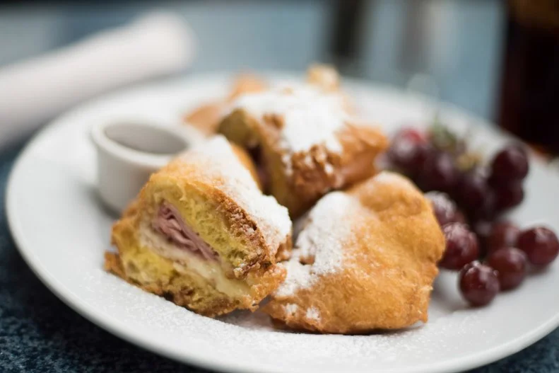 Café Orleans has welcomed hungry park-goers in New Orleans Square since 1966, yet we wouldn’t urge you to dine there based on nostalgia alone. The Monte Cristo sandwich with pommes frites is one big reason enough to recommend the old-timer. First, that sandwich: Kind of like a croque-monsieur, it is filled with turkey, ham and Swiss cheese; battered and fried; and topped with powdered sugar and pureed berries. Its partner on the plate has its own destination status. These french fries are tossed with garlic, parsley and Parmesan cheese, then served with a spicy Cajun remoulade. At lunchtime, you can get that same Monte Cristo at the more upscale Blue Bayou. The only catch: It comes with a fruit skewer instead of the fries, and it costs a bit more.