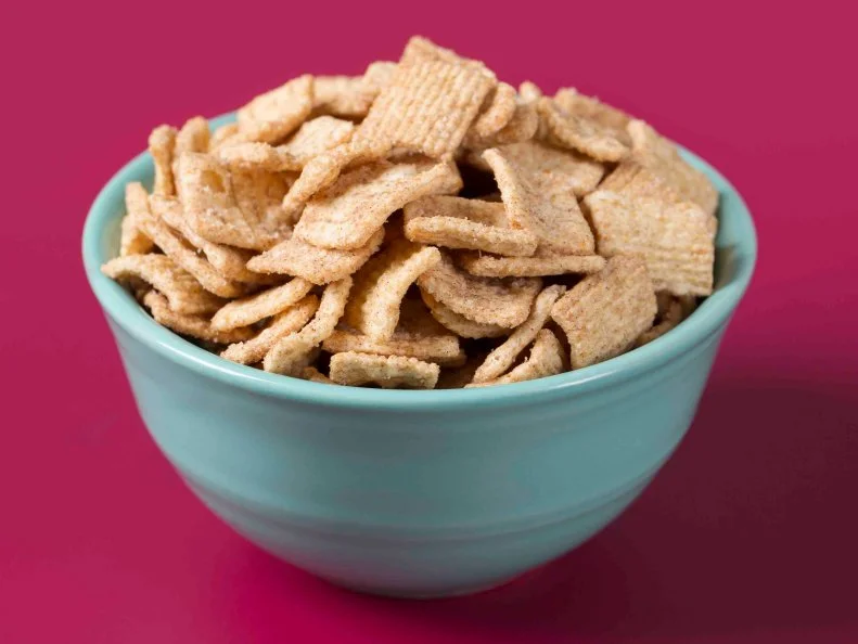 Cinnamon flavored breakfast cereal in a blue bowl on a magenta background