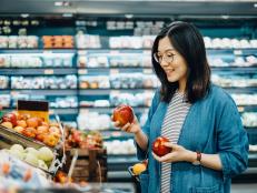 Young Asian woman shopping for fresh organic fruits in supermarket