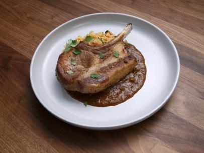 Anne Burrell's Seared Pork Chop and Mole Sauce with Corn and Tomato Rice is displayed, as seen on Worst Cooks in America, Season 17.