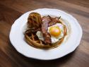Bobby Flay's Open-Faced Cornmeal Waffle Sandwich with Maple and Mustard Glazed Bacon and Fried Egg is displayed, as seen on Worst Cooks in America, Season 17.