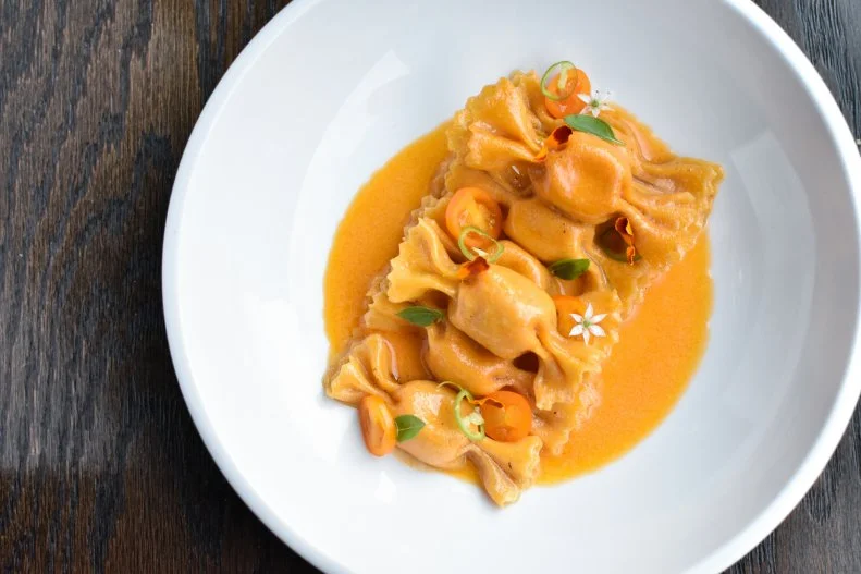 Made in the shape of a candy with the high-dose sweetness of sun gold tomatoes, this gorgeous pasta is a celebration of summer’s bounty. Every component uses those little rounds of sun-ripened fruit. There are sun golds in the sauce, dotting on top and inside the caramelle pasta (a shape that hails from the Lombardy region of Northern Italy) along with some smoked ricotta to add some cream and Texas-style smoke. To root the Italian dish in the Lone Star State, Juniper chef de cuisine Zach Riddle peps it up with some Tex-Mex flavors including serrano chiles, lime zest and oregano, which he says, “are much-beloved, familiar and nostalgic to the people of Austin.”