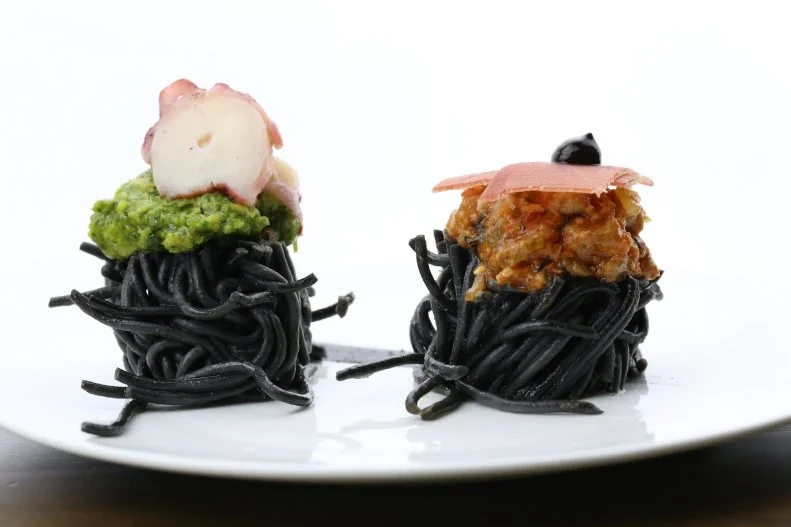 The one problem with ordering pasta in a restaurant is that it can be so filling, it’s hard to try multiple versions. That’s not an issue at The Sea Fire Grille in Midtown Manhattan, where chef Jesus Nunez serves two-in-one squid ink pasta bites. The two bites have different preparations, so you can sample multiple squid ink pasta presentations on a single plate. One is a tuna bolognese in which the traditional beef is swapped out in favor of small chunks of tuna in the hearty tomato sauce, finished with a piece of tuna prosciutto on top. The other features a pistachio and fava bean pesto nestled around the strands with slice of octopus on top. It’s definitely great for Instagram and it’s a lovely couple of bites while sipping a glass of wine at the bar.