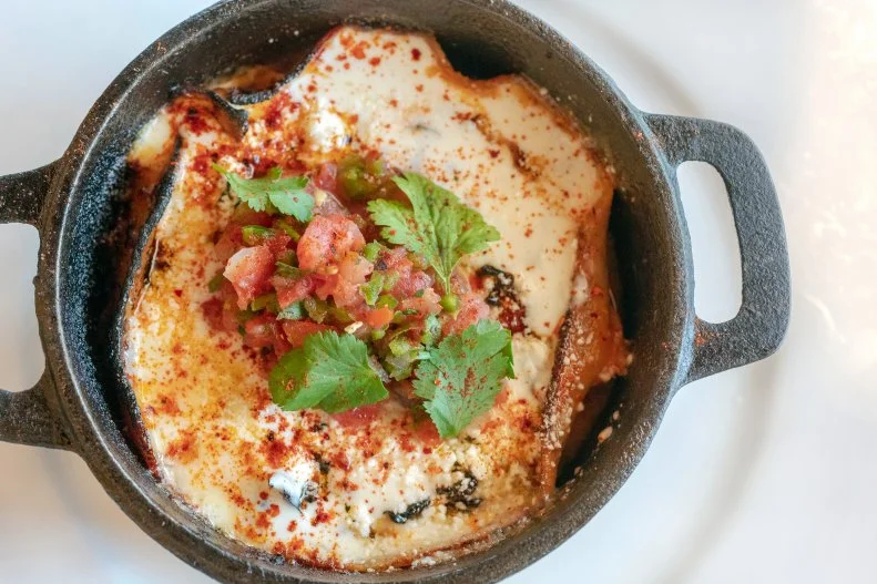 Cousins and co-chefs Roberto Centeno and Rene Andrade bring Southwest cuisine from back home to Phoenix with dishes that are reflective of the Sonoran-style Mexican food that they grew up eating in Nogales, Arizona, a border town located 60 miles south of Tucson. Gooey, cheesy, creamy Aztec cakes were a way to use up day-old tortillas. At Ghost Ranch they are baked with roasted green chiles, corn and shredded chicken and served in a tiny cast iron pot.