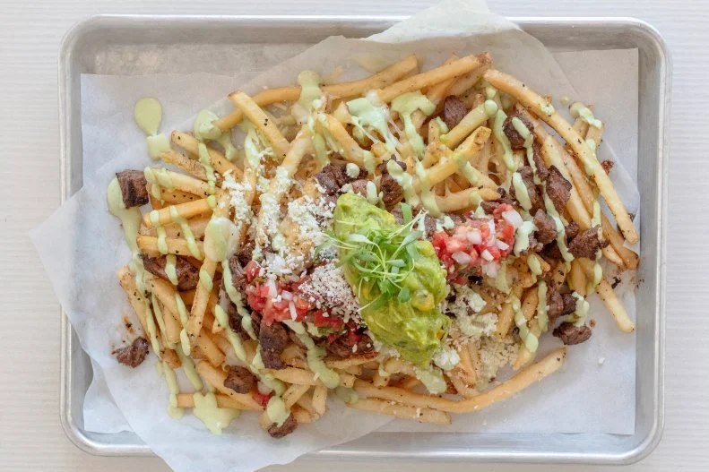 The ambiance at Taqueria Centro is light and airy with white floors and floor to ceiling windows on three sides with sweeping views of Phoenix’s Camelback Mountain helmed by Chopped champion Laura Gonzalez. The food is Sonoran and central Mexican. The carne asada fries fall somewhere between cheese fries and nachos. You can’t really scoop the carne asada, guacamole and pico de gallo salsa up with a fry like you can with a tortilla chip, so a fork is recommended to get all of the parts speared in a way where they can go evenly into your mouth.
