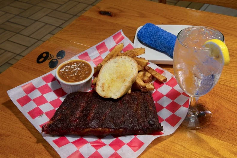 “[David and I] were drinking at the beach, retired and bored, when we conjured up the idea to open Hoots BBQ,” says owner Susie Powell. The full-service restaurant and bar might be off the beaten path in McGehee, Arkansas, but people travel near and far, especially when en route to the beach by way of Louisiana or Mississippi, to feast. If nearby and car windows are down, you’ll be lured in by the scent of ribs cooking in the air.