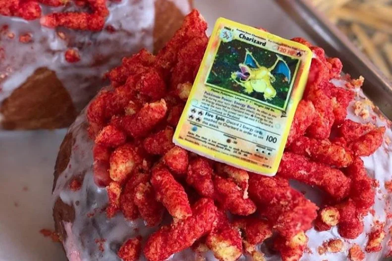 Pokémon fans will find a special treat here: an edible version of one of the favorite trading cards. Named after one of the characters, Charizard, this doughnut is just as fiery as its namesake. The brioche doughnut is stuffed with a hot Cheetos mousse, glazed in buttermilk, and topped with some more hot Cheetos and an edible replica of a Pokémon trading card.