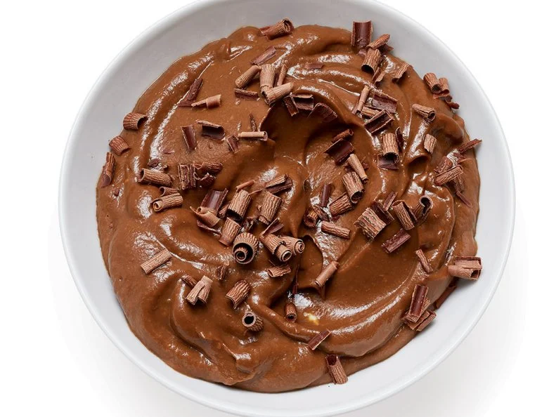 Mix 2 tablespoons unsweetened Dutch-process cocoa powder with 2 tablespoons hot water until smooth. Puree with 1 large ripe avocado, 3 tablespoons maple syrup, 1/2 teaspoon vanilla and 1/4 teaspoon salt, adding 1 to 2 tablespoons water and more maple syrup, if needed. Divide between 2 small bowls. Refrigerate until chilled, 30 minutes. Top with shaved dark chocolate.