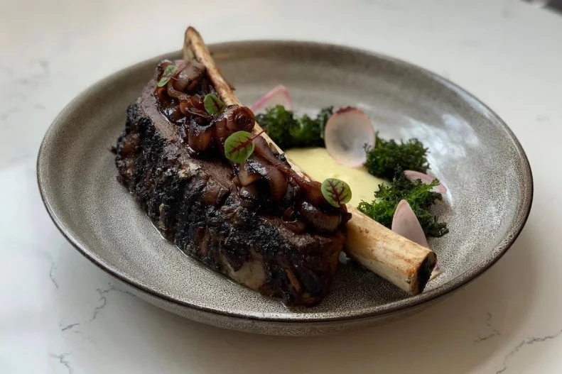 You’ll find pops of art deco all over Nashville, especially inside the L&C Tower, an iconic mark on the city’s skyline. Deacon’s New South sits at the base of the building and pulls some of that inspo into its own space. The heart of this contemporary steakhouse is the glassed-in kitchen where the grill sits front and center and a dry-aging room to the side shows off the day’s butcher cuts. The menu here puts a modern spin on fine cuts of meat and Southern staples. The selection of steaks ranges from strips to a tomahawk ribeye to A5 Japanese wagyu. Build a meal around one of those with a starter like chow-chow deviled eggs, a cup of gumbo Ya-Ya, and sides of crispy brussels sprouts or braised collard greens. The thoughtful wine list matches the menu with a strong selection of American and old-world reds. 