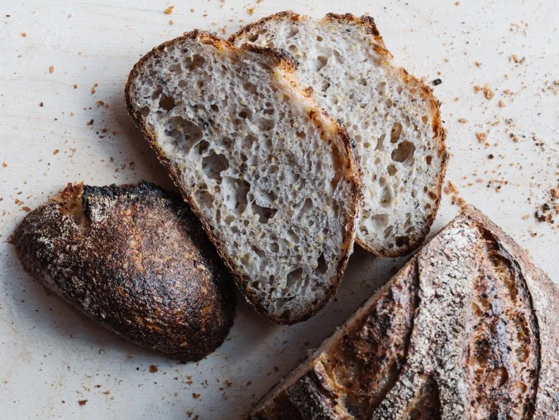 Chris Wilkins discovered bakery life the way many cooks find kitchen life — as a side gig while in graduate school. He fell for life as a baker, fine-tuning his craft under Randy George of Red Hen Bakery before moving to Athens to help open Independent Baking Co. with Thom Leonard, who many credit with the resurgence of heirloom grains. They started <a target="_blank" href="http://www.rootbaking.com/">Root Baking</a> in 2015 with a focus on Southern grains. They relocated from Charleston to Atlanta’s Ponce City Market in 2018, where they sell combinations like a sourdough loaf folded with cooked aromatic Charleston Gold Rice from Anson Mills and benne seeds (pictured). They also incorporate regional ingredients like sorghum and locally grown Cateto corn into a lightly sweet grits-inspired loaf. That combo is also fashioned into a slab-style pie that takes a starring turn on Root Baking’s pizza night, alongside cracker-thin focaccia filled with mozzarella. 