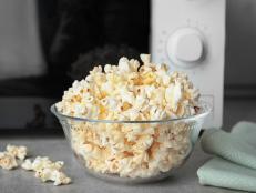 Glass bowl with tasty popcorn on table in kitchen