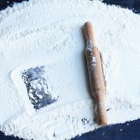 Rolling pin and white flour on a dark background. Free space for text. Top view.