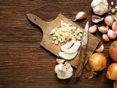 Garlic cloves and onions on wooden vintage background