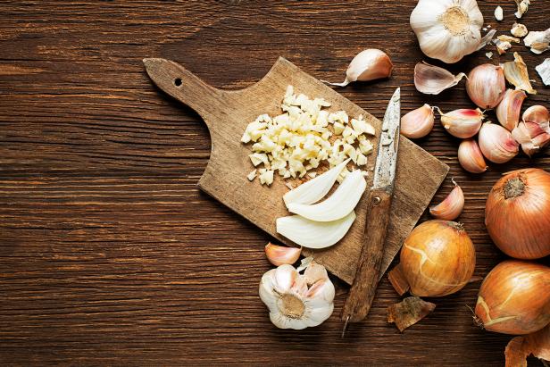 Garlic cloves and onions on wooden vintage background