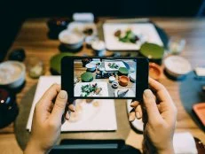 Woman's hand taking a picture of delicate Japanese style cuisine with various side dishes, miso soup and main dishes with smartphone