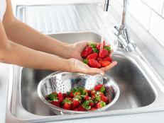 Woman is washing strawberry in the kitchen.