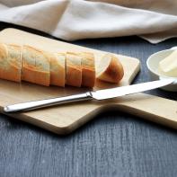 Traditional breakfast. Bread (sliced baguette) on cutting board with butter on plate on dark wooden background. (Traditional breakfast. Bread (sliced baguette) on cutting board with butter on plate on dark wooden background., ASCII, 112 components, 11