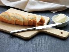 Traditional breakfast. Bread (sliced baguette) on cutting board with butter on plate on dark wooden background. (Traditional breakfast. Bread (sliced baguette) on cutting board with butter on plate on dark wooden background., ASCII, 112 components, 11