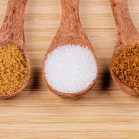 Three wooden spoonfull of different sugars, light brown sugar, dark brown sugar, and granulated sugar on a wooden background (Three wooden spoonfull of different sugars, light brown sugar, dark brown sugar, and granulated sugar on a wooden background,