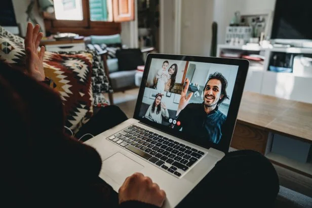 Young woman using a laptop to connect with her friends and parents during quarantine. She's having a video conference during Coronavirus COVID-19 time.