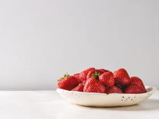 Fresh organic garden strawberries in ceramic plate on white marble table. Copy space.