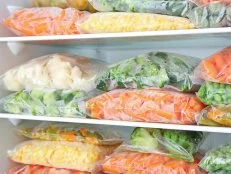 Plastic bags with deep frozen vegetables in refrigerator