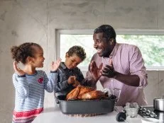Fathers preparing thanksgiving turkey with his kids