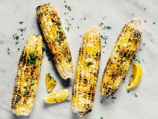 Grilled corn with spices and herbs on white background