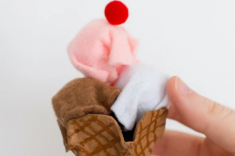 Tuck the scoops into the cone and top with a red pom-pom to be the cherry on top. 